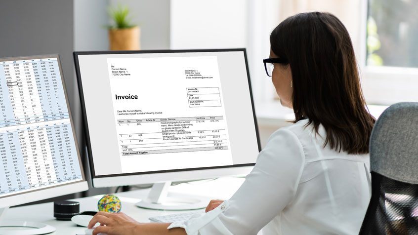 Female associate paying invoices at her desk.