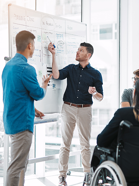 coworkers talking with whiteboard in background