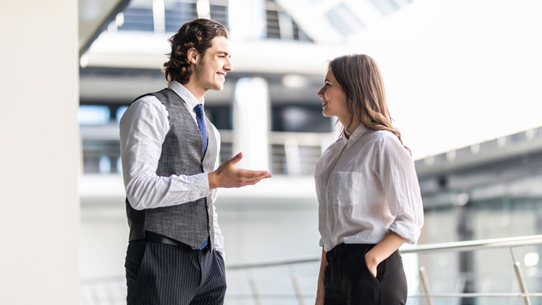 Two colleagues chat with each other outside of their office building.