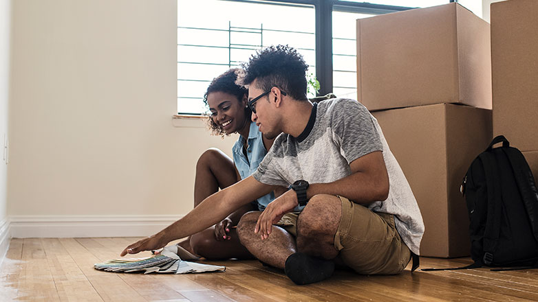 Young couple hanging out in their new home surrounded by boxes.