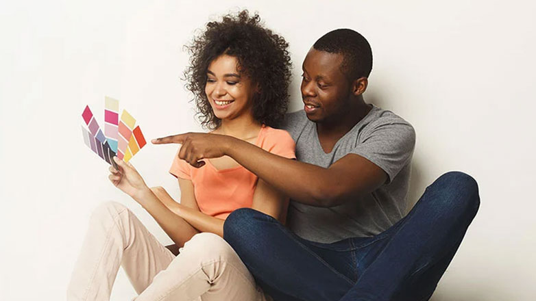 Young couple sitting together looking at paint swatches.