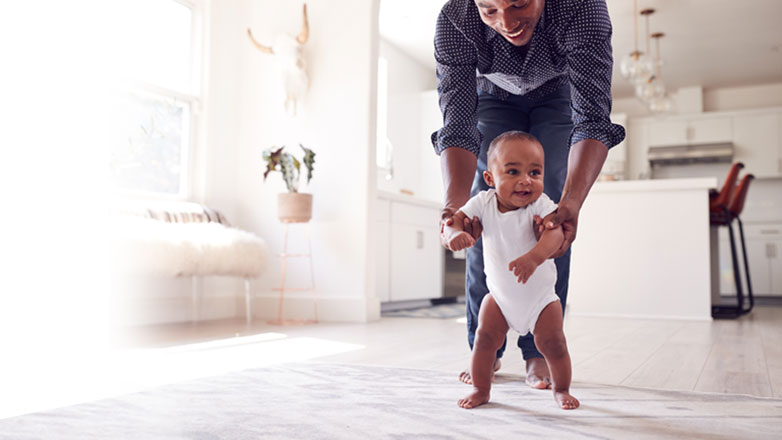 Dad helping his baby take their first step.