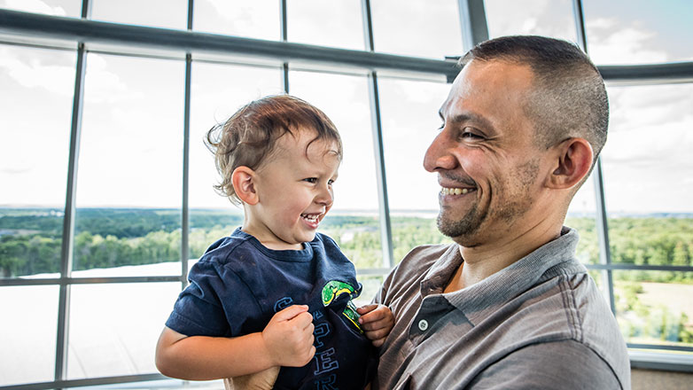 Father holding young son in an atrium setting.