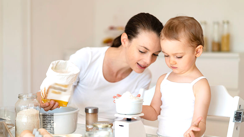 Mom and young daughter baking a cake.