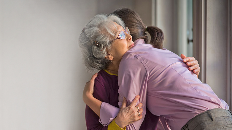 Daughter consoling mom witha hug.