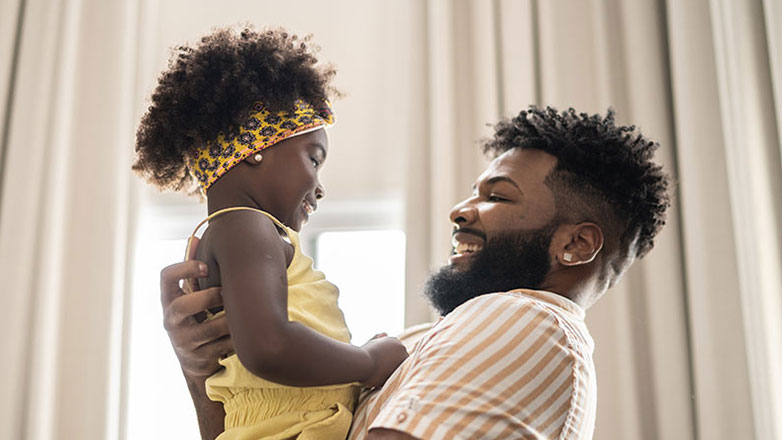 Father plays with his young daugther in their living room.