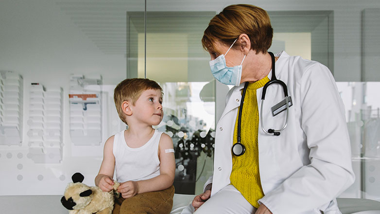 Female physician sitting on bed visiting with a child