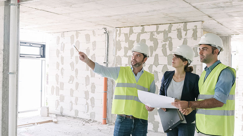 A female and two males looking at the struture of a concrete building.