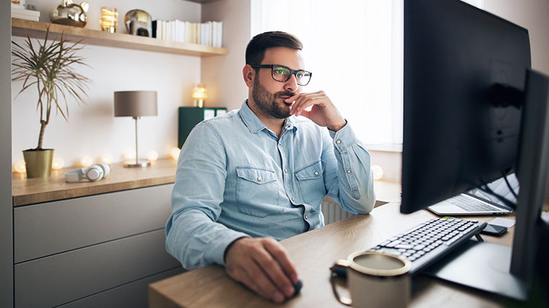 A man works on his computer from his home office.