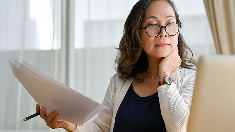 Mature woman examines her checking account on her laptop.