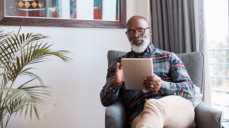 senior man sitting in chair using tablet