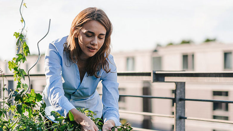 Woman working on her rooftop garden outside.