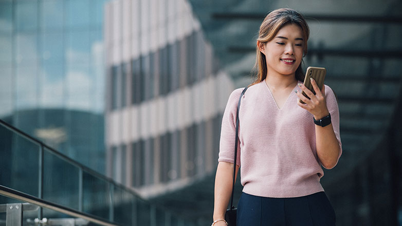 A woman checks her smartphone on her walk to work.