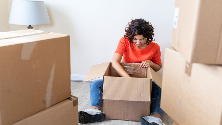 Woman sitting on the floor surrounded by boxes.