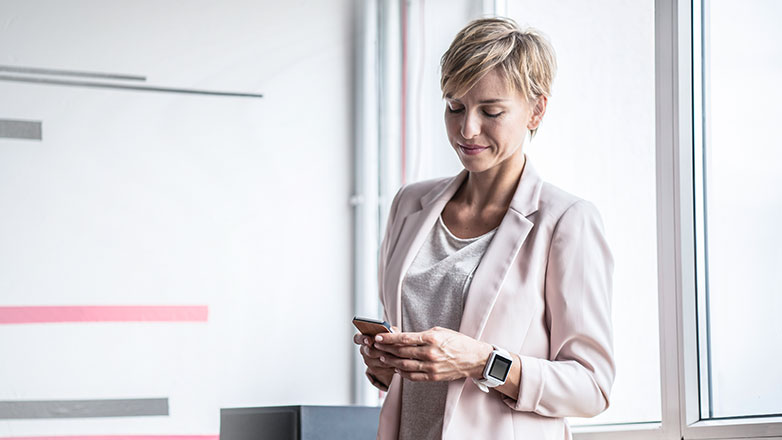 Female professional standing in heroffice looking at her phone.