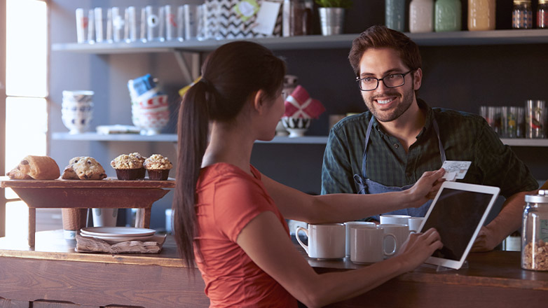 woman using a tablet to pay for her purchase at a small business.