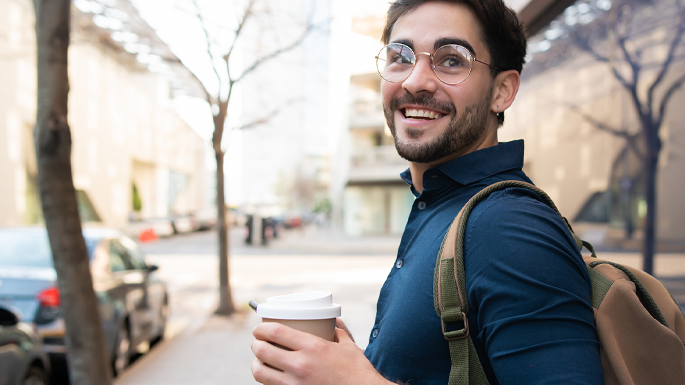 A happy young man holding a cup of coffee.