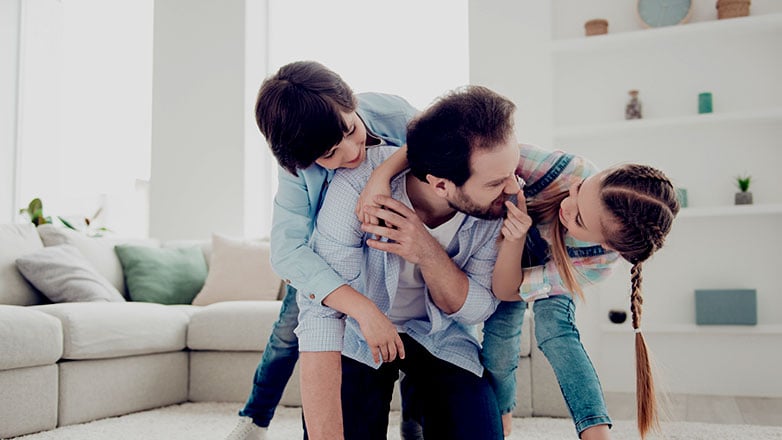 Father on the floor playing with his son and daughter.