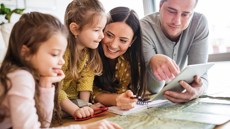 Mom, dad and daughters looking at a map to pick next vacaton destination.