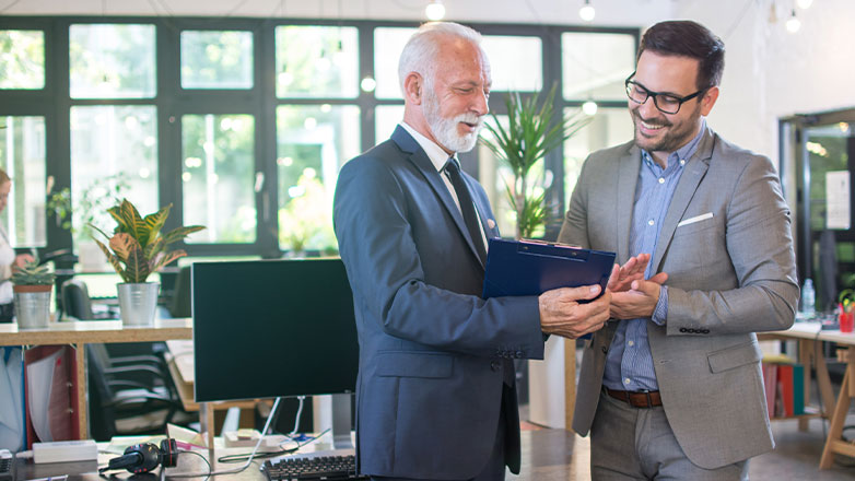 father teaching son business practices on clipboard in office