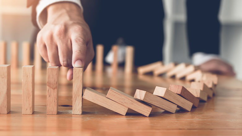 finger stopping chain of dominos from falling