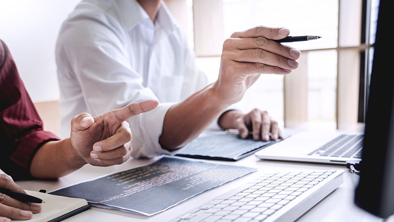 Two male co-workers pointing to a computer screen.