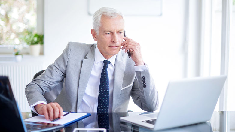 man on phone at desk looking at computer