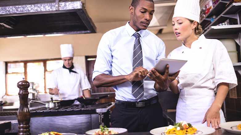 manager and cook discussing business on tablet in kitchen