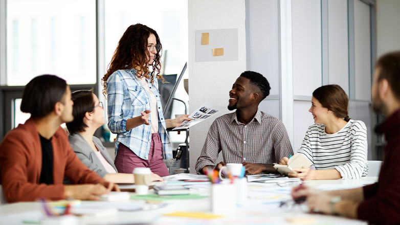 several employees meeting around table and smiling