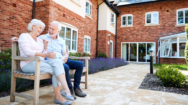 two seniors sitting outside living home