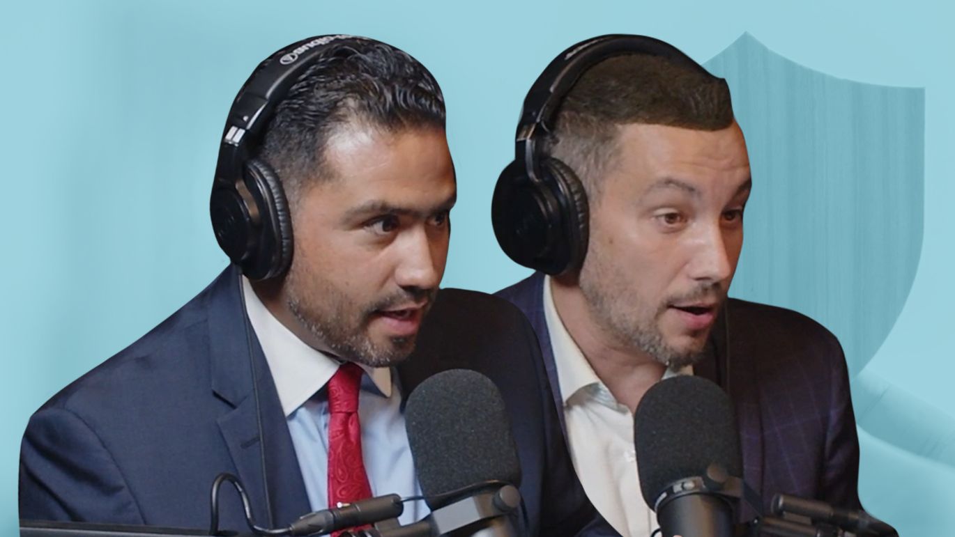 Two people wearing headphones speaking into microphones with a shield graphic in the background.