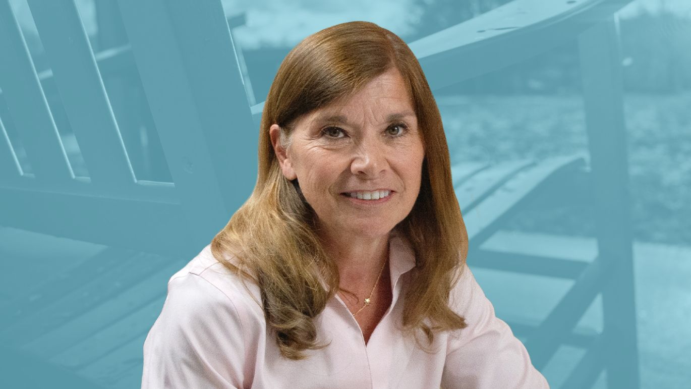 Headshot of a person in front of a blue-toned background featuring outdoor Adirondack chairs.