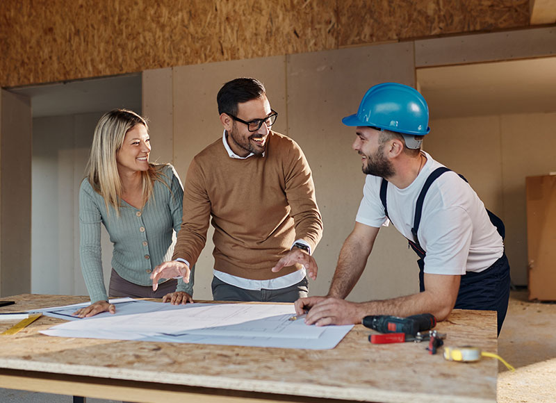 Contractor reviews building plans with homeowners.