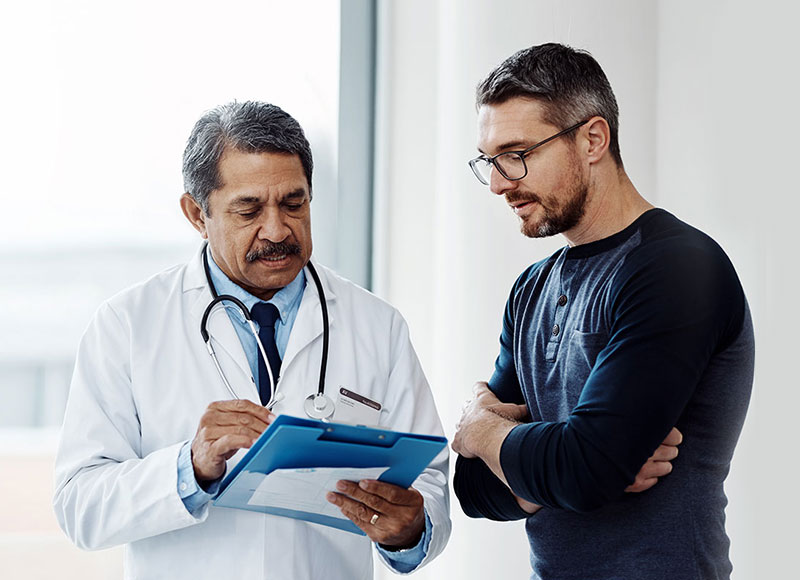 Older doctor reviews chart with his patient.