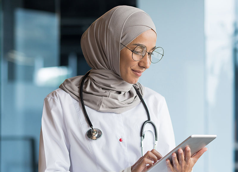 A young physician reviews notes on a tablet.