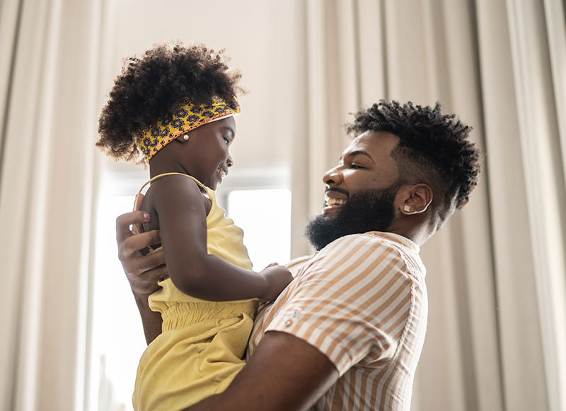 Father plays with his young daugther in their living room.