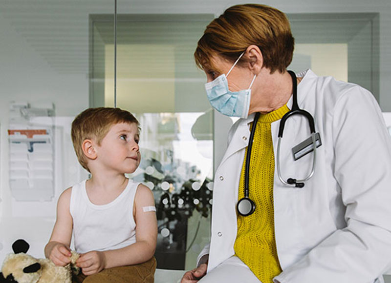 Physician checks on young patient after administering an injection.