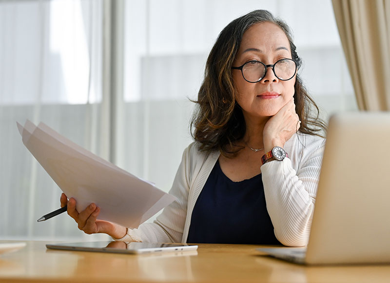 Mature woman examines her checking account on her laptop.