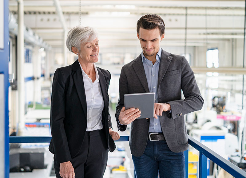 Son discusses business succession plan with his mother in a factory.