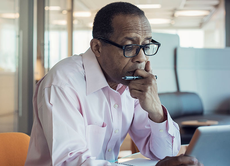 Man working in his office looking at his tablet with a serious expression.