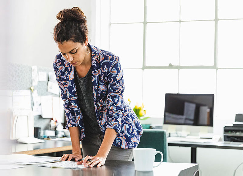 Woman standing at her desk and reading through papers.