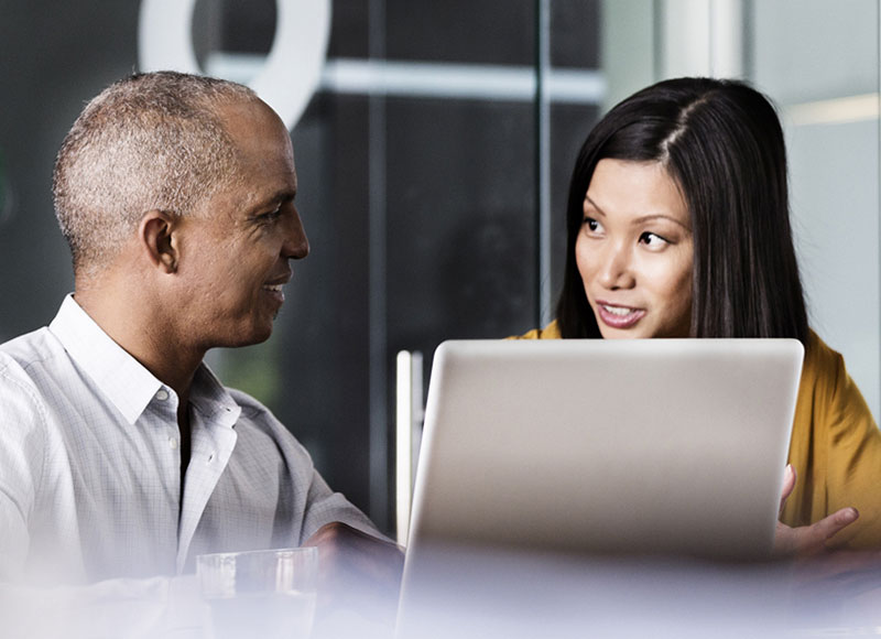 Business colleagues sit at a table and work at a laptop together.