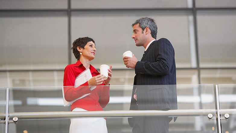 Two work colleagues have a chat over coffee.