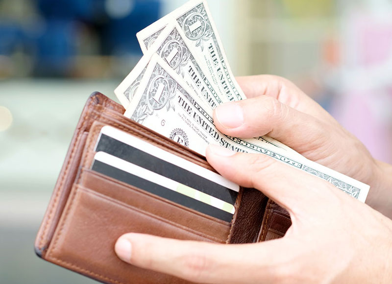 Close-up of hands removing bills from their wallet.