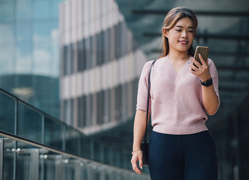 A woman checks her smartphone on her walk to work.