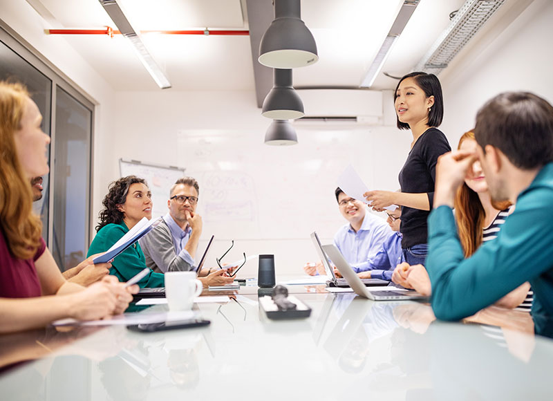 A woman speaks to her team at a meeting.